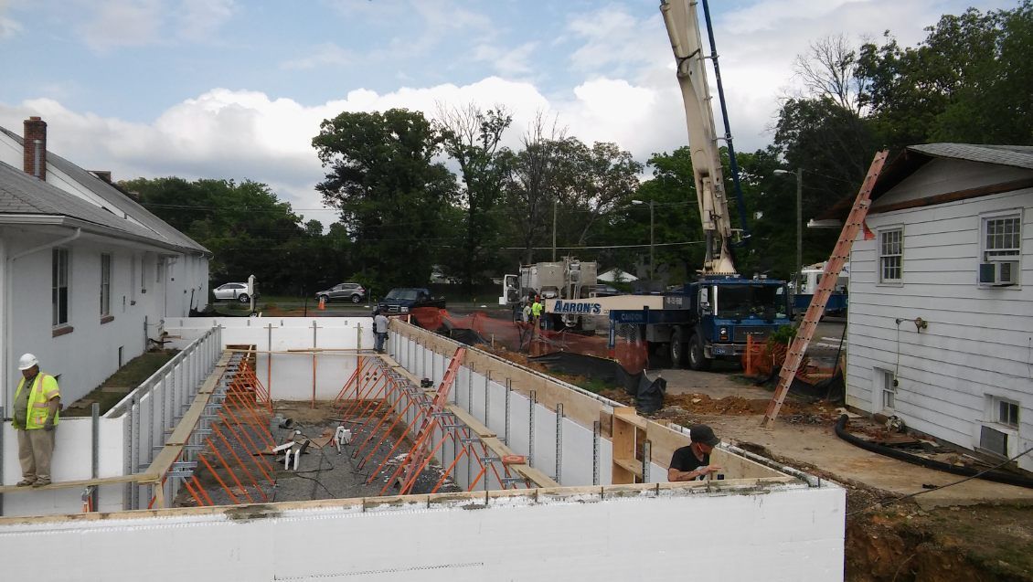 A crane is being used to pour concrete into a building under construction