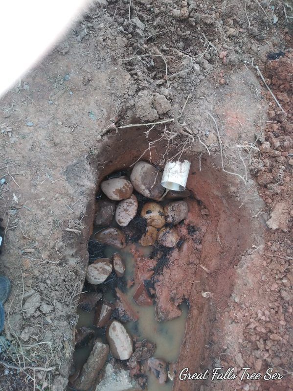 A hole in the ground with rocks and a pipe in it.