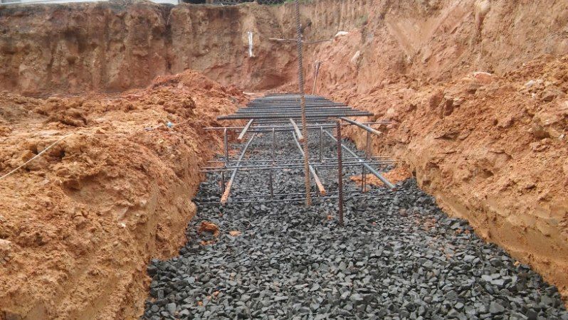 A trench filled with gravel and dirt with a metal structure in the middle.