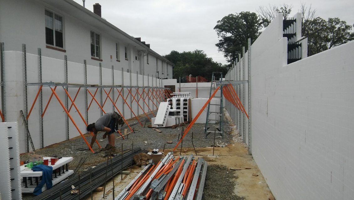 A man is working on a construction site in front of a building.