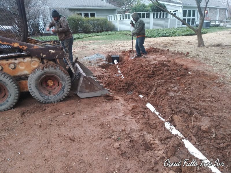 A man is digging a hole in the dirt next to a bulldozer.