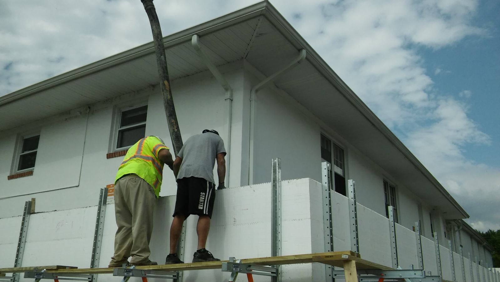 Two men are working on the side of a building