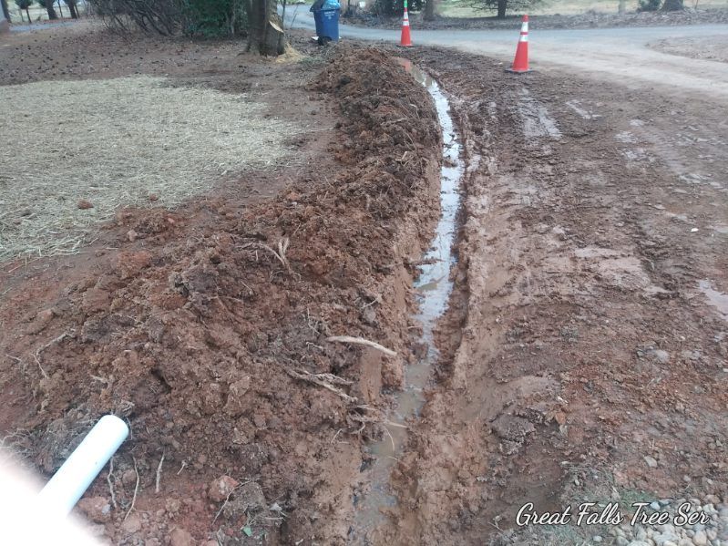 A muddy road with a white pipe in the middle of it.