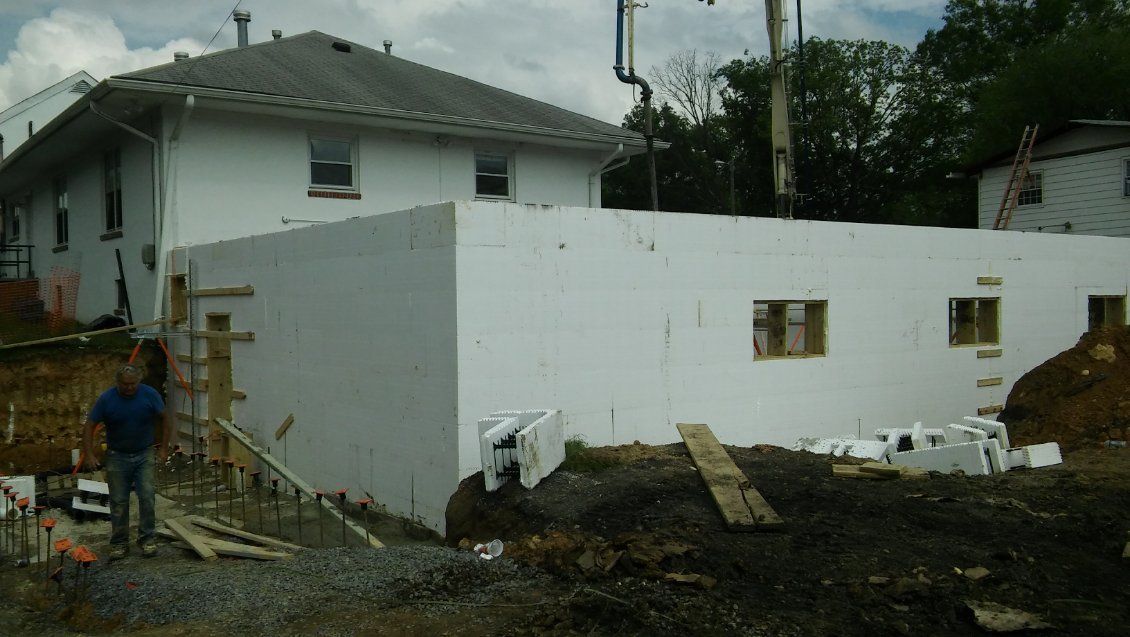 A man is standing in front of a white house under construction.