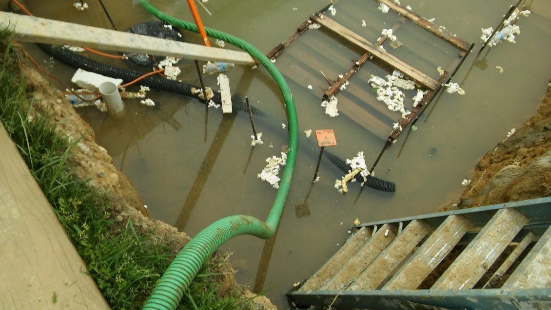A green hose is being used to pump water out of a flooded area.