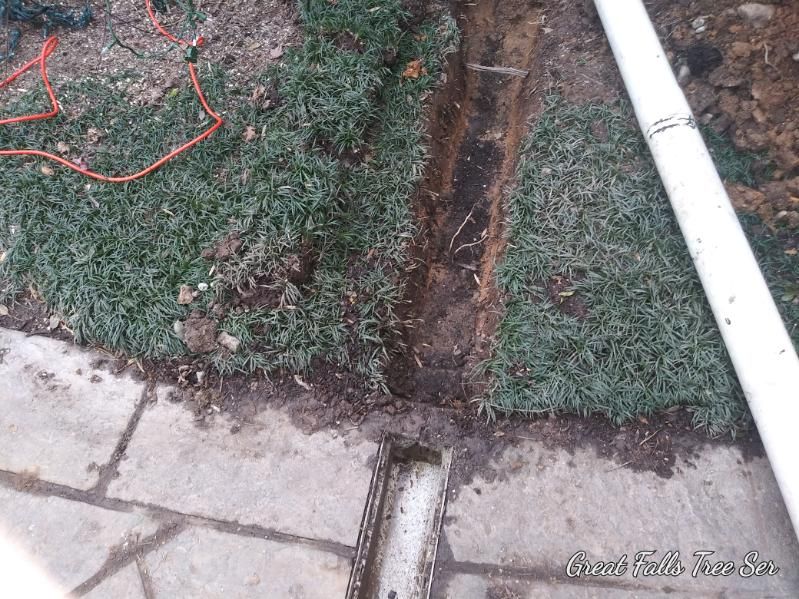 A white pipe is laying on the ground next to a chainsaw.