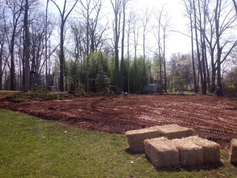 A pile of hay bales sitting on top of a lush green field.