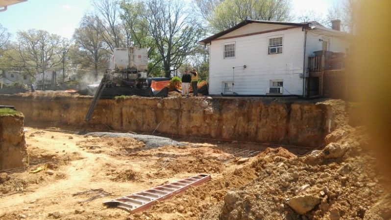 A construction site with a house in the background and a ladder in the foreground.