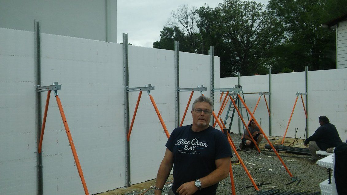 A man wearing a shirt that says big chills is standing in front of a white wall.