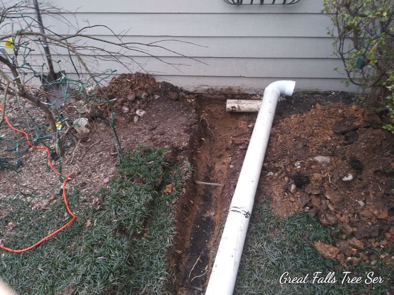 A white pipe is sitting in the dirt next to a house.