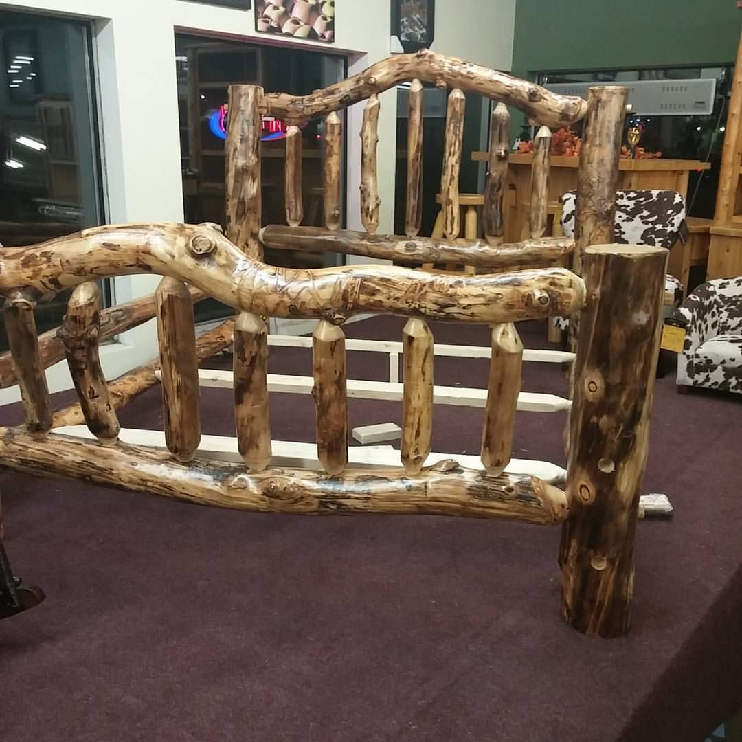 Rustic wooden bed frame with log details on a purple carpet.