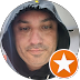 Close-up of a man in a dark cap against a teal background, with an orange star badge overlay in the corner