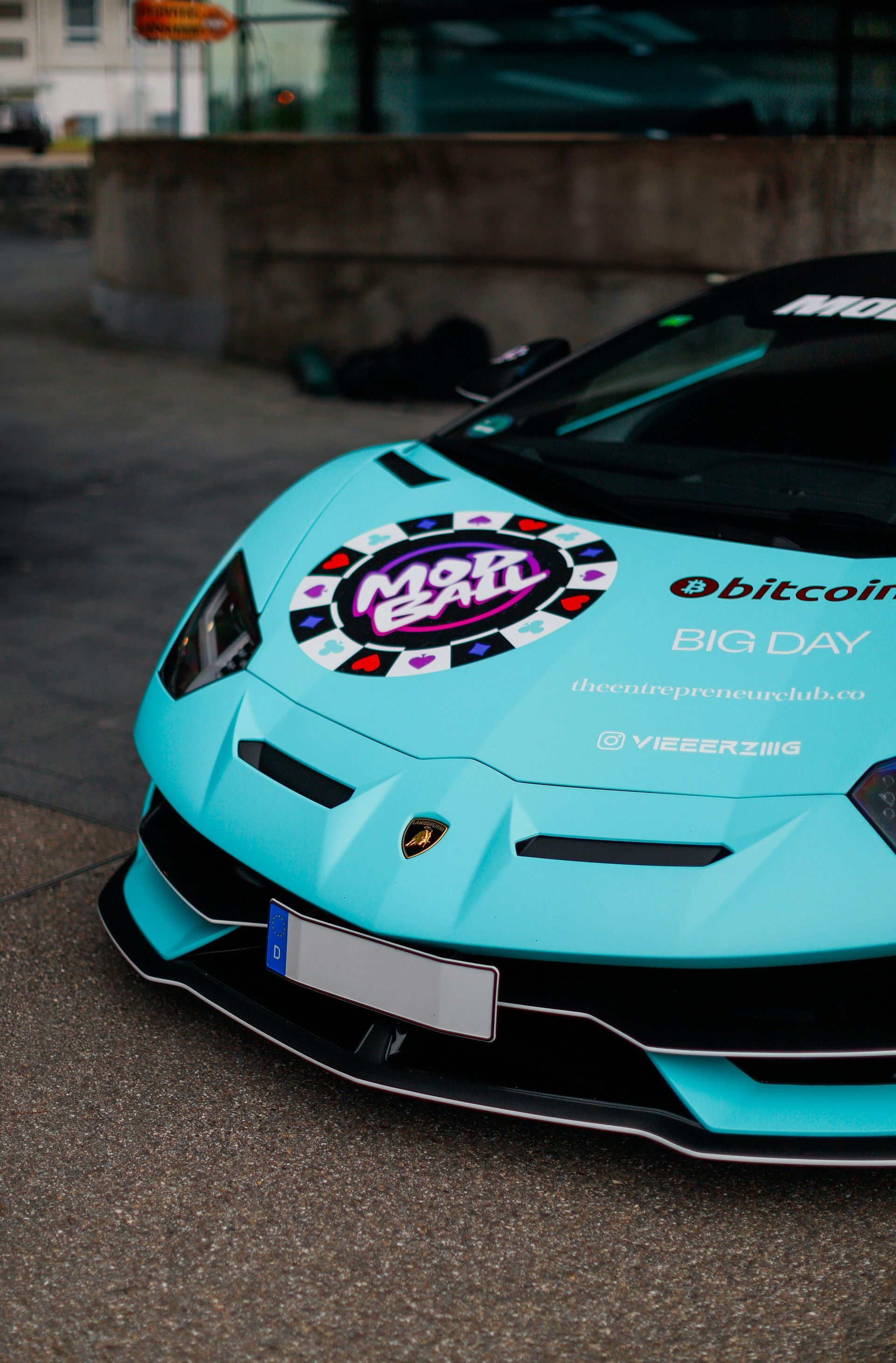 Turquoise Lamborghini race car front view with sponsor decals parked outdoors