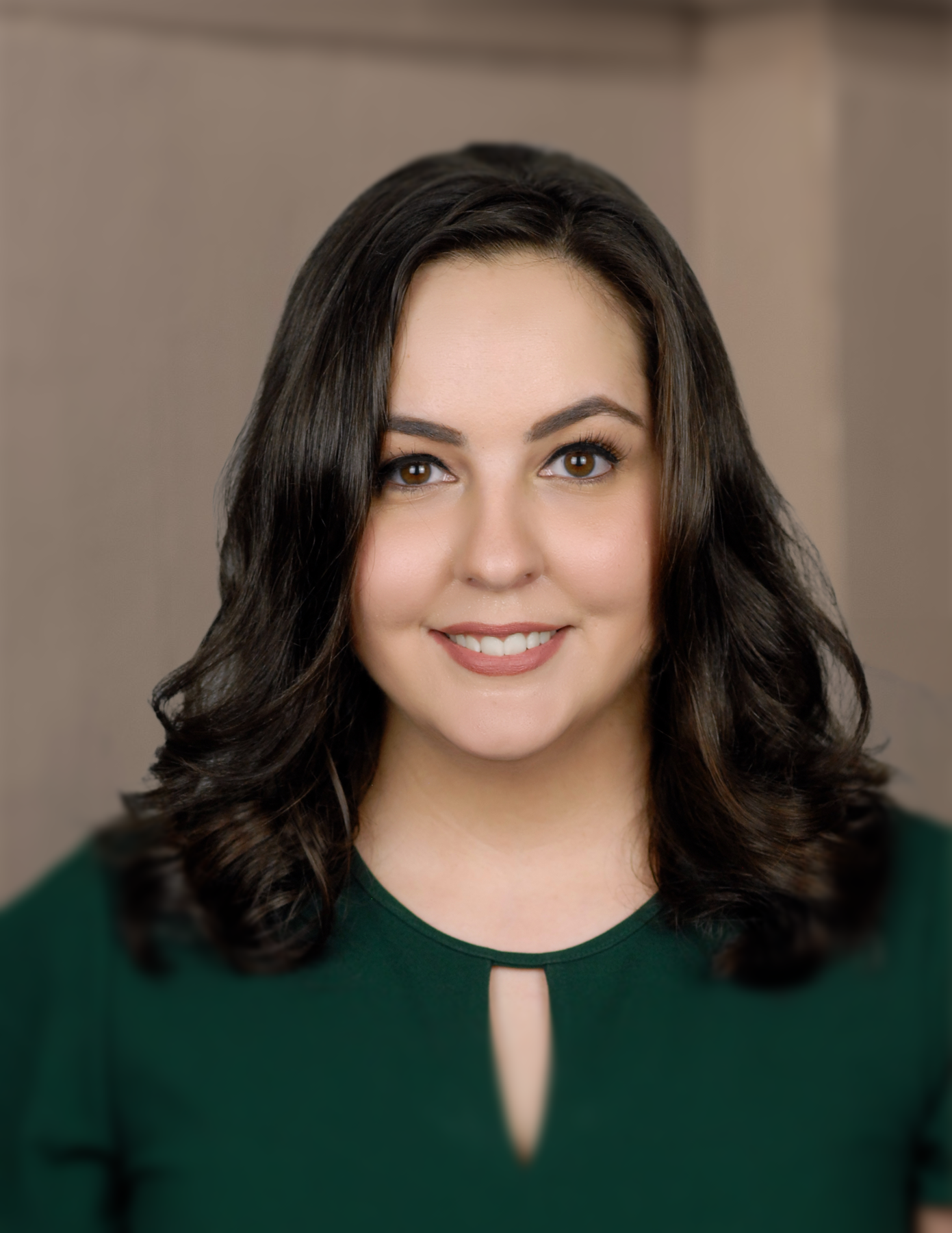 A woman in a green shirt is smiling for the camera.