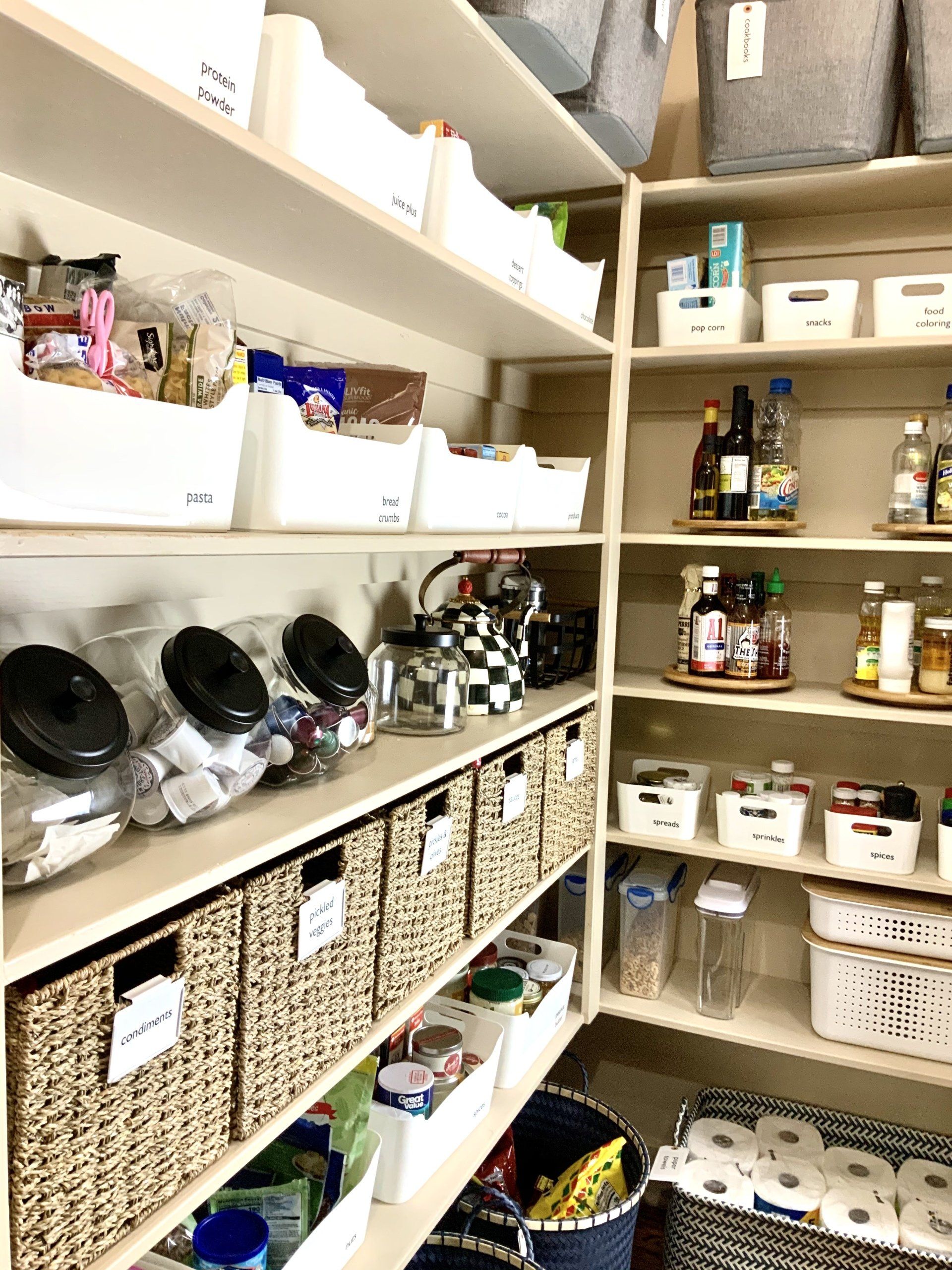 Large pantry wall organized with sea grass bins, white containers with handles, Mackenzie child’s accents, back stock and glass jars.