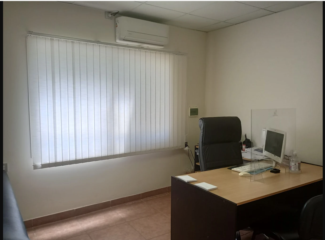 Una habitación con un escritorio y sillas y una ventana grande.