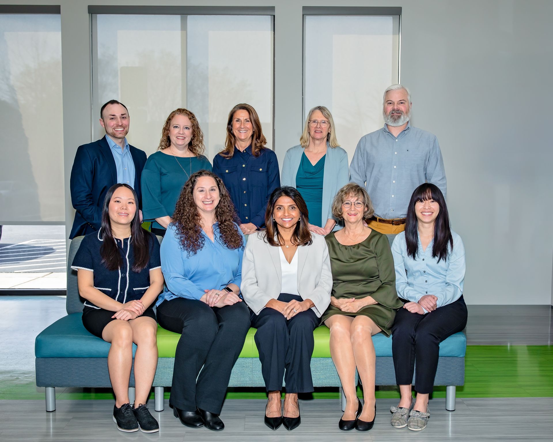 Group of nine people posing together in an office setting.