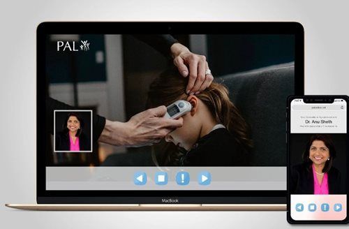 Laptop and phone displaying video of a person checking a child's temperature with an ear thermometer.