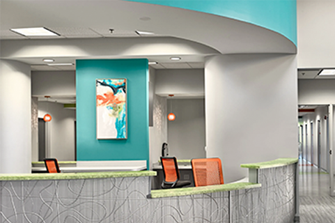 Modern office reception area with teal and orange accents, artwork, and curved walls.