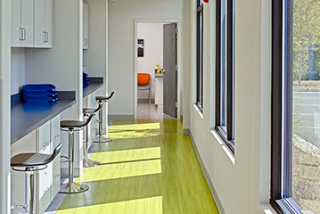 Bright hallway with lime green floor, counter with stools, and windows.