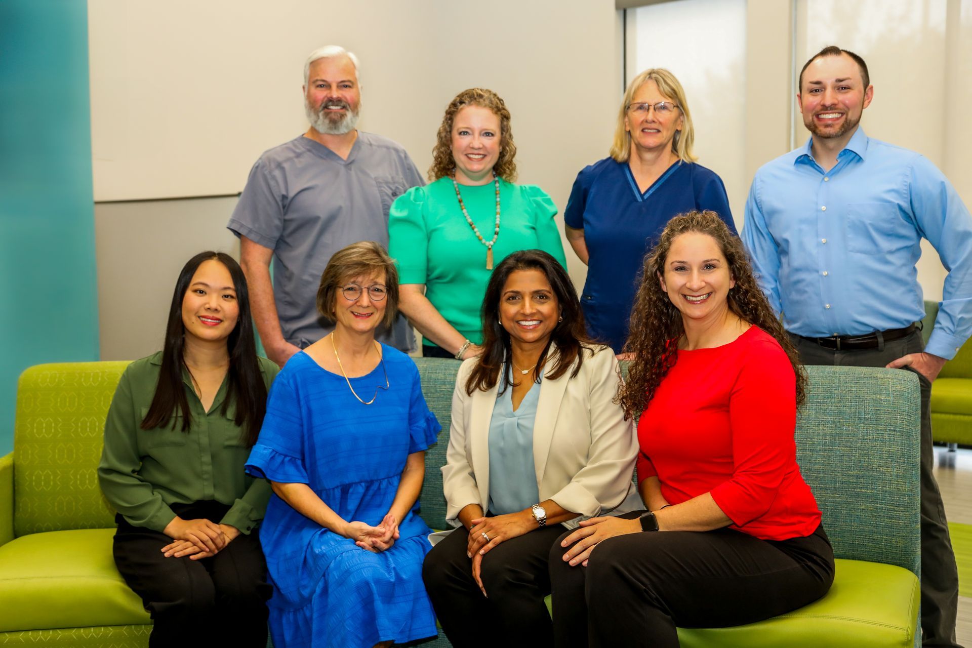 Group of nine people posing together in an office setting.