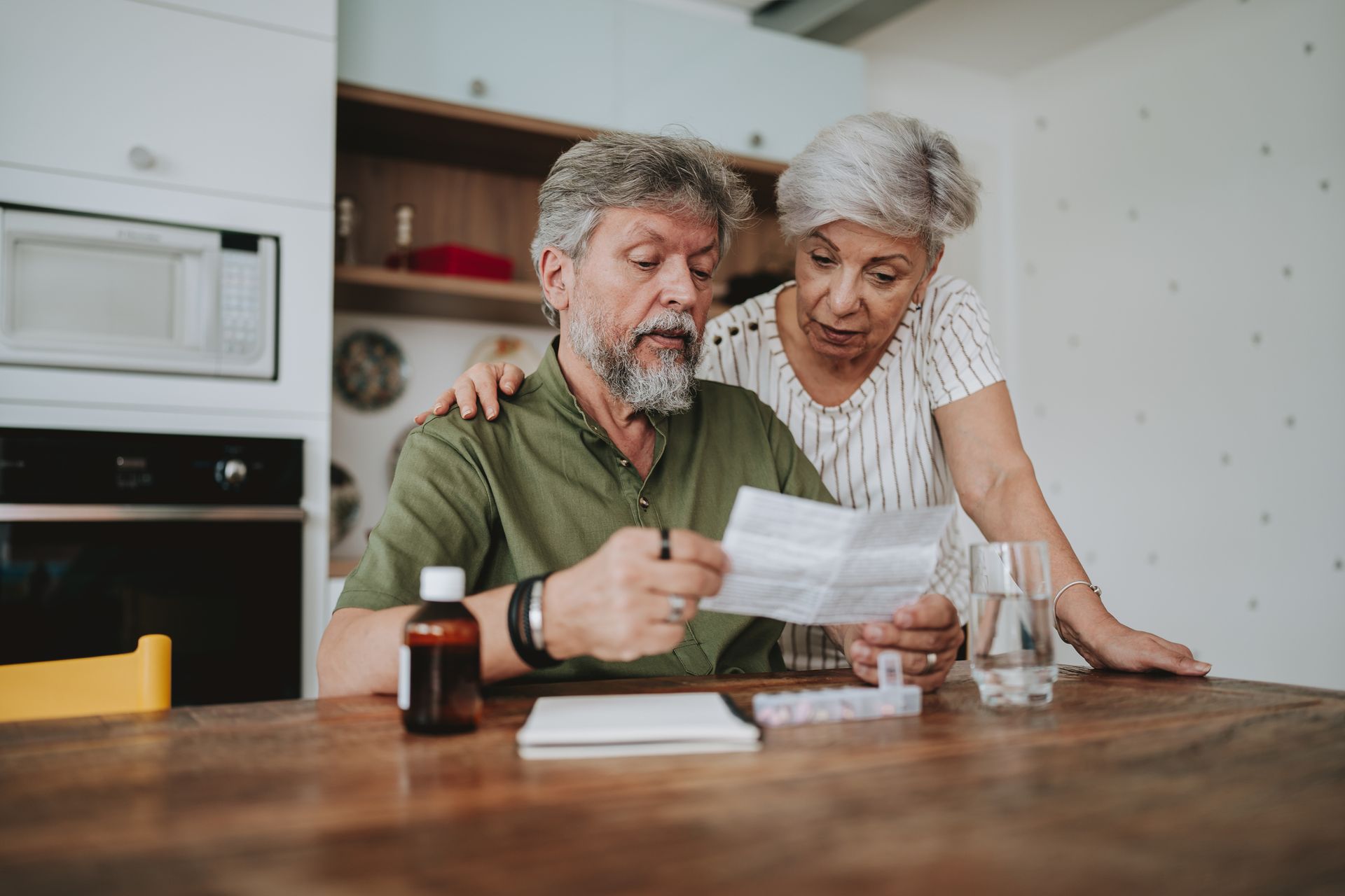 An elderly couple is sitting at a table looking at a prescription.