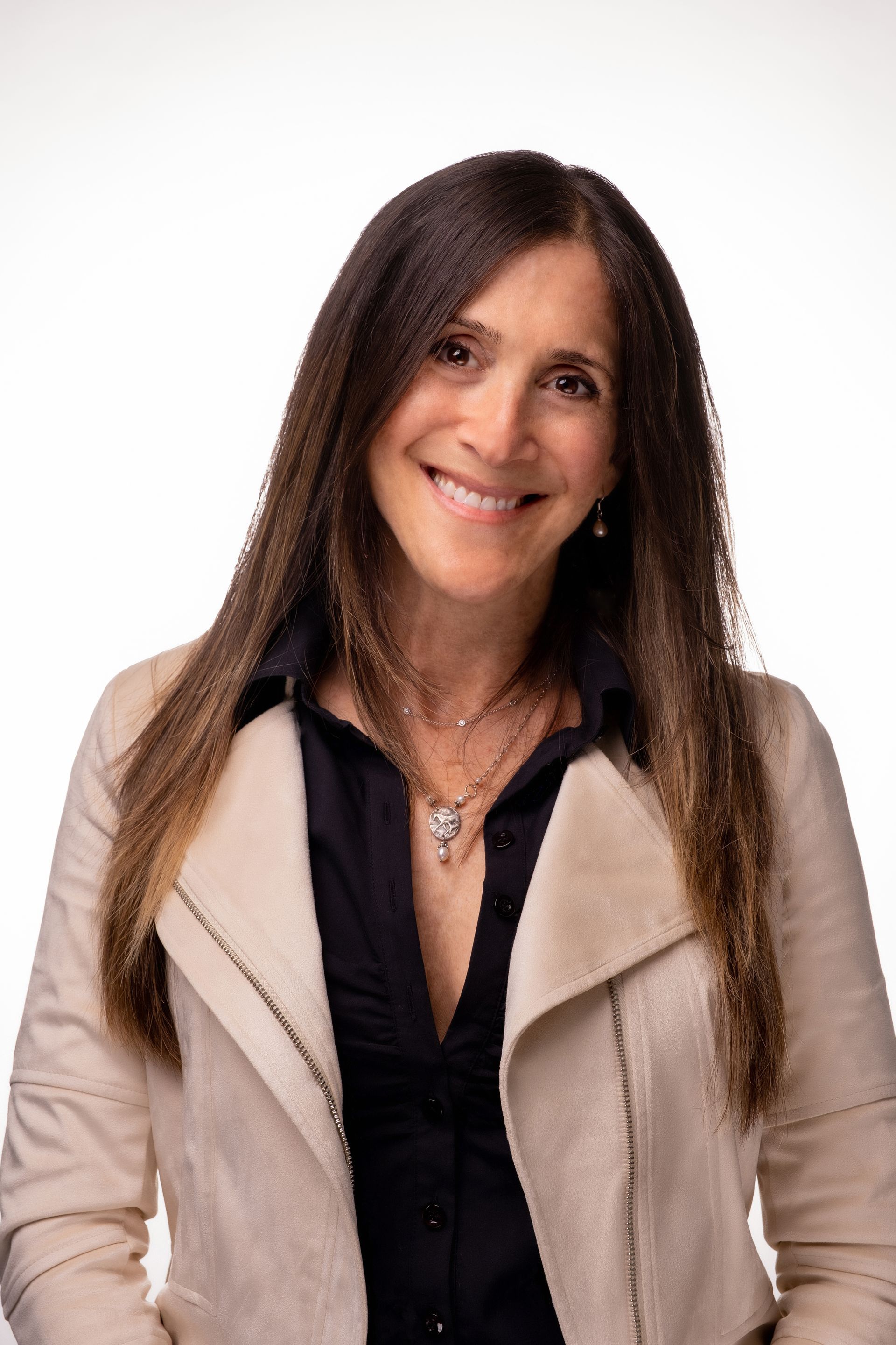 A woman wearing a white jacket and a black shirt is smiling for the camera.