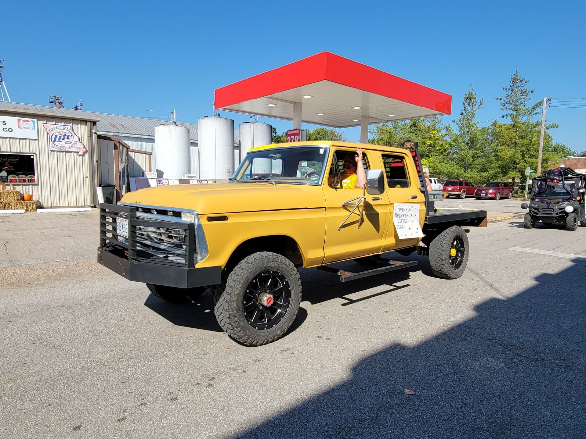 A yellow truck is parked in front of a gas station.