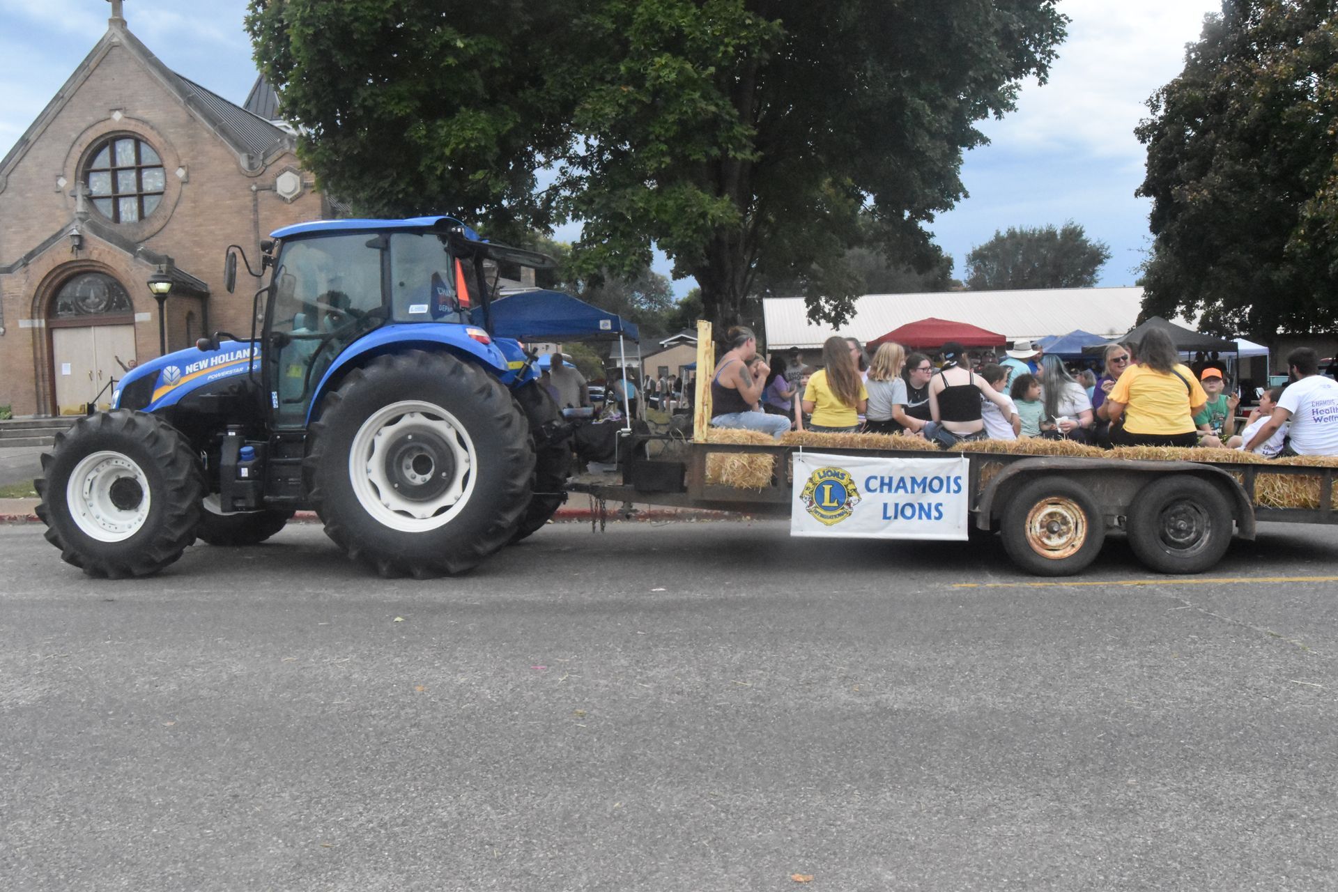 A tractor pulling a trailer with a sign that says church lions