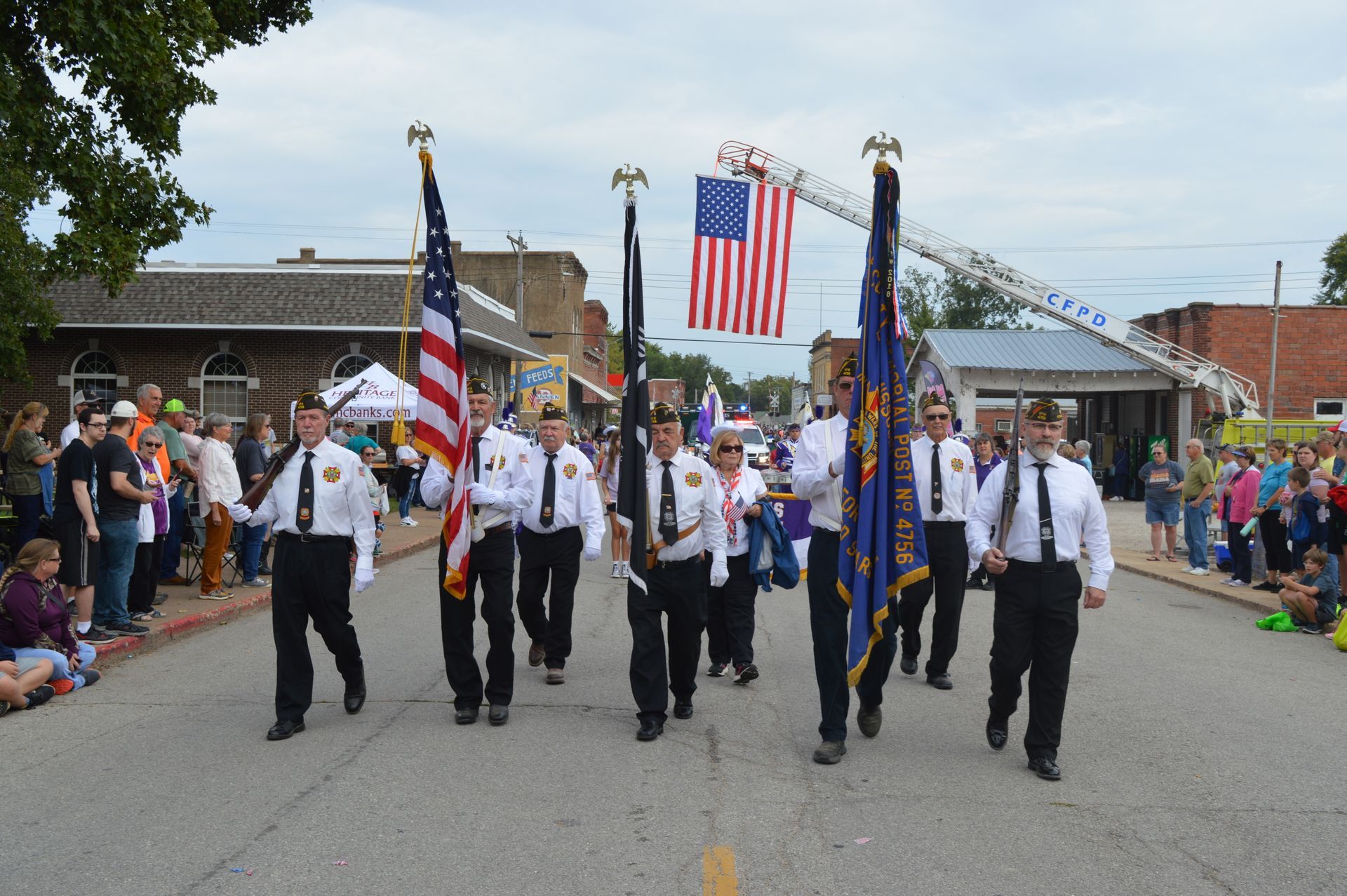 A group of men are marching down a street holding flags.