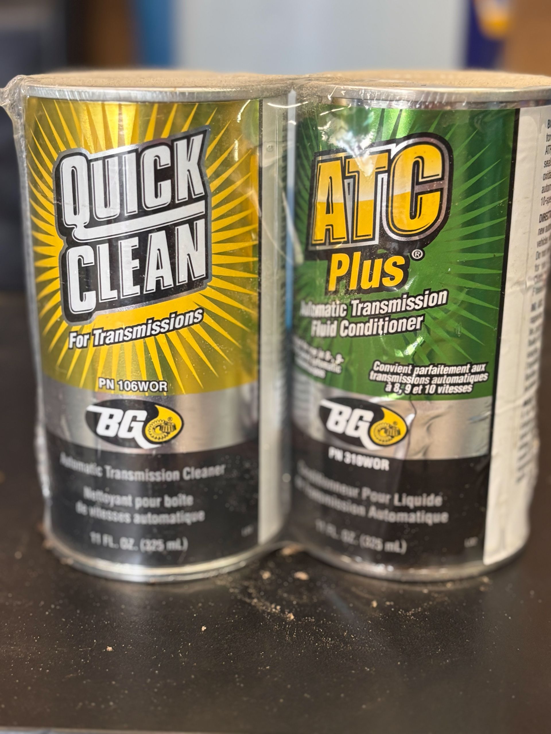 Two cans of quick clean and atc plus are sitting on a table.