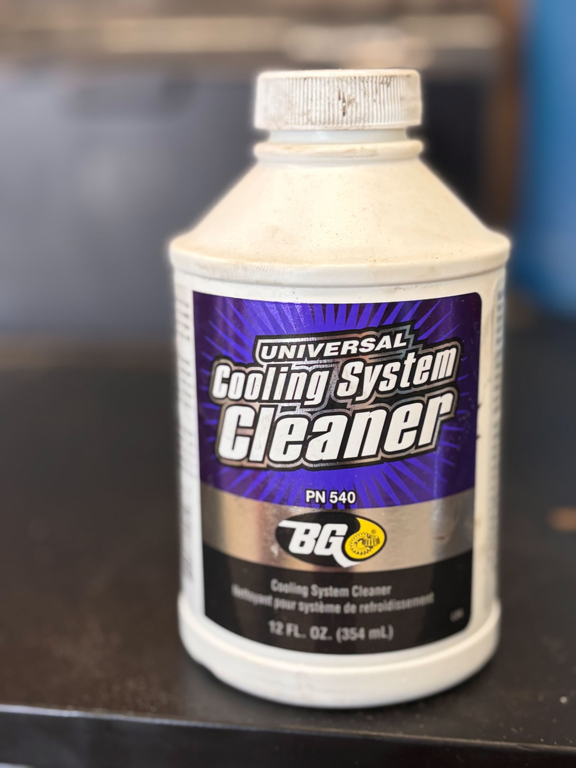 A bottle of universal cooling system cleaner is sitting on a table.