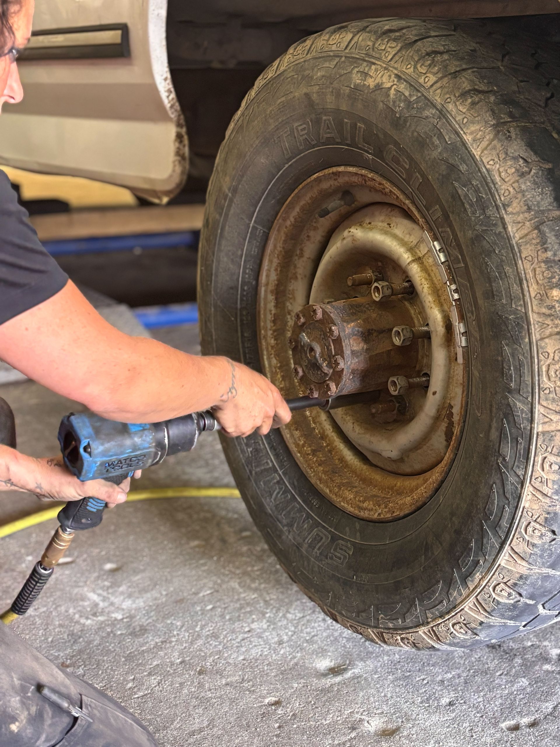 A man is changing a tire on a truck with a wrench.