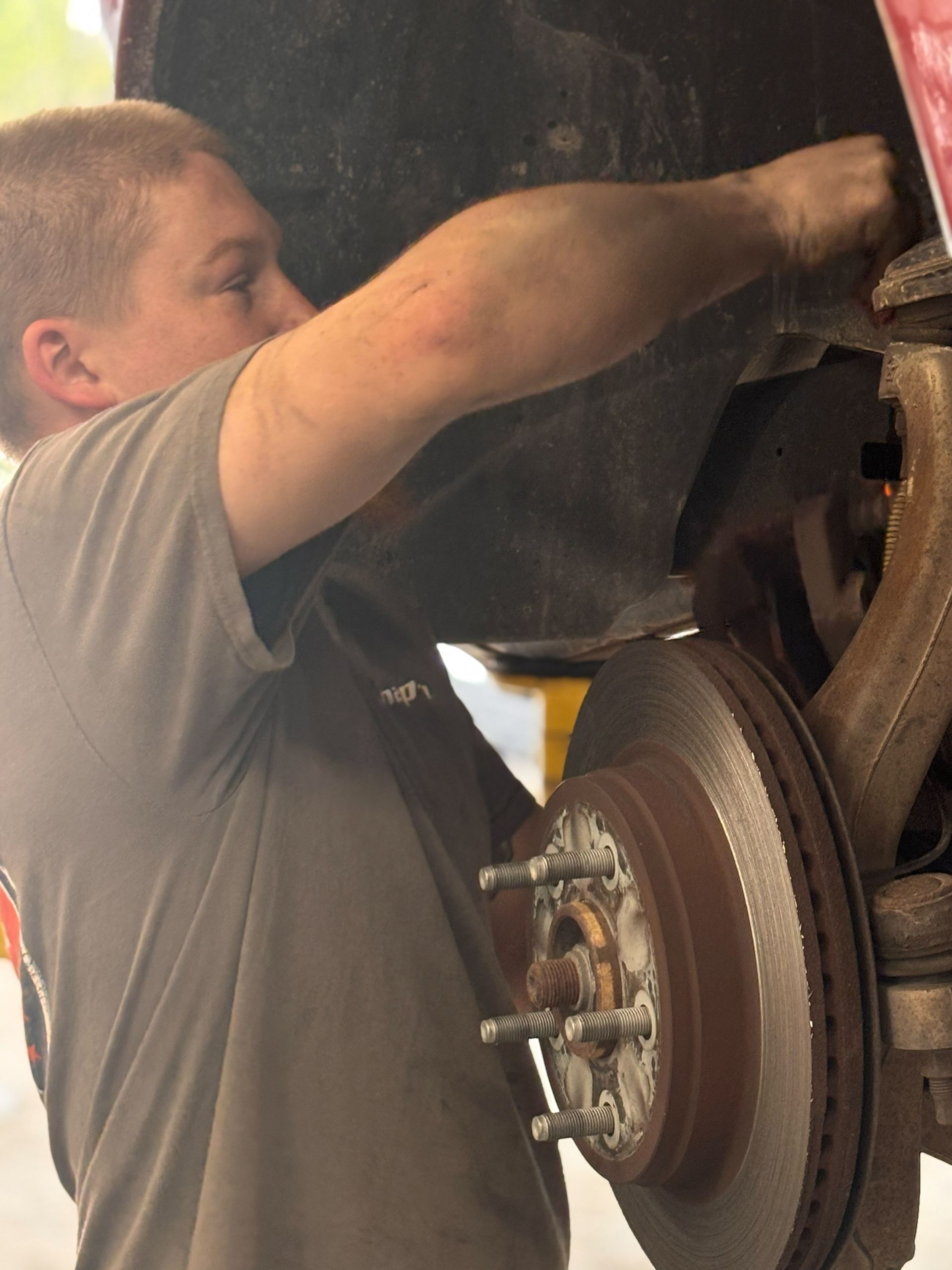 A man in a grey shirt is working on a car