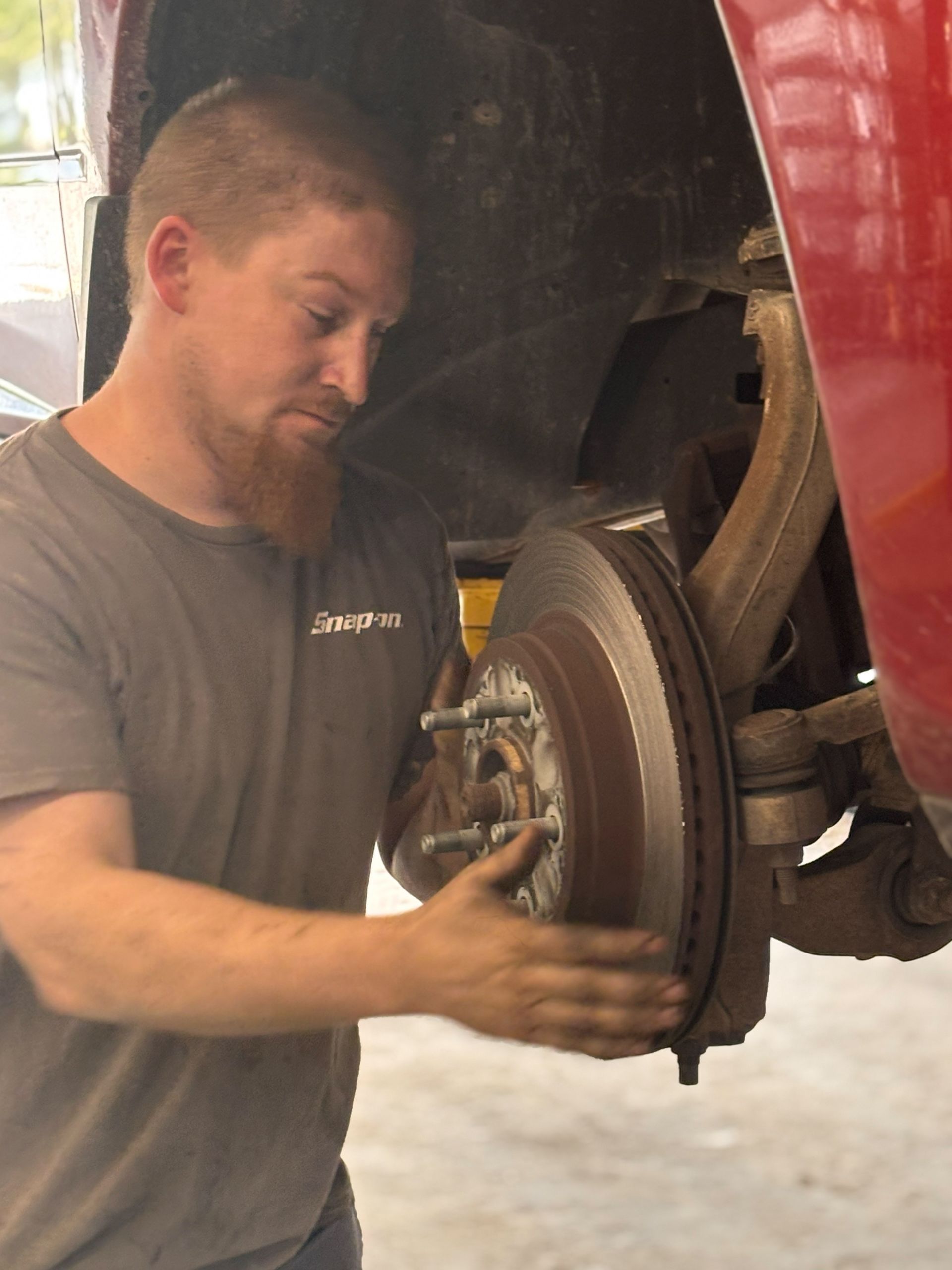 A man in a grey shirt is working on a brake disc