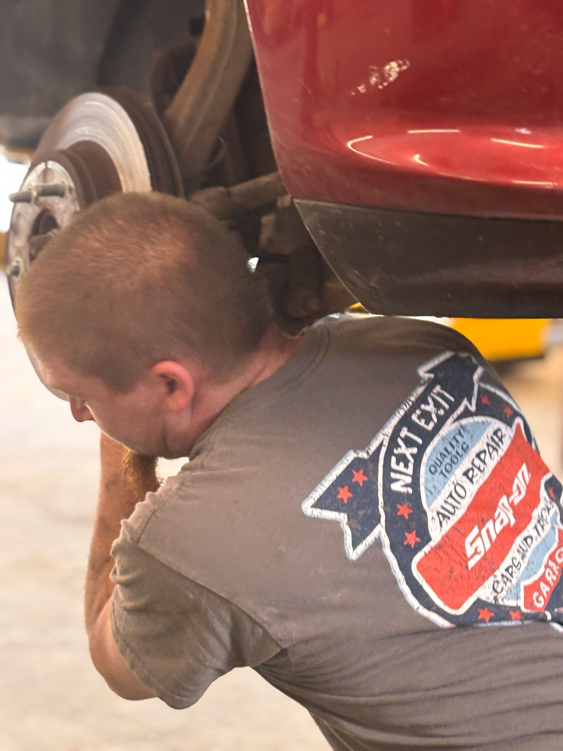A man wearing a snap on shirt is working on a car