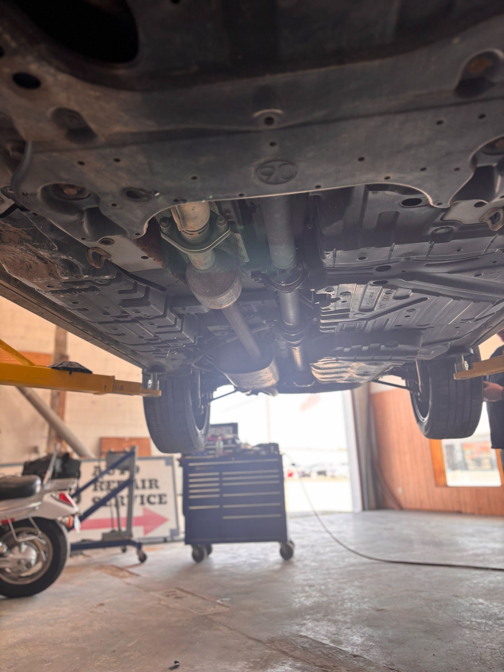 The underside of a car is shown in a garage