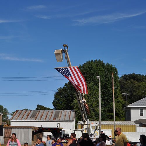 A group of people standing around a pole with an american flag on it