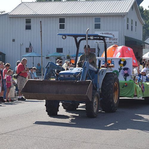 A man is driving a ford tractor in a parade at Chamois Day in Missouri