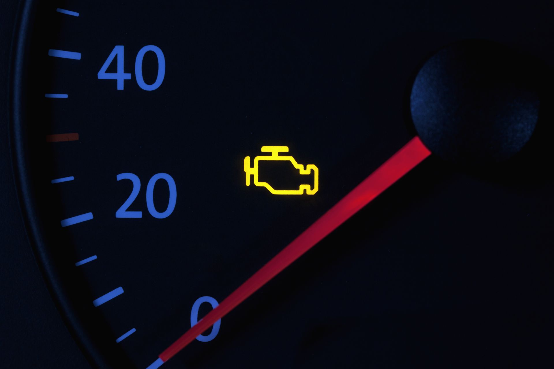 A close up of a speedometer with a yellow engine light on it