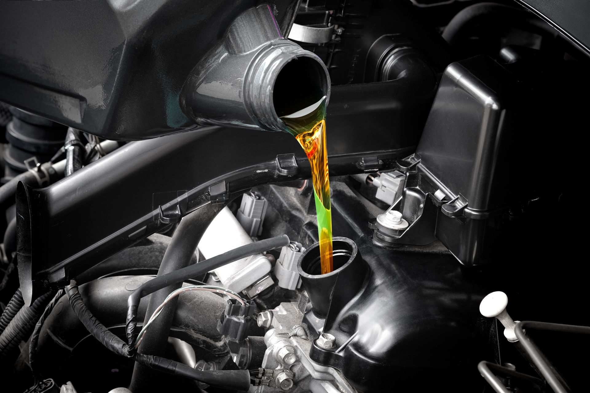 A close up of a person pouring oil into a car engine.