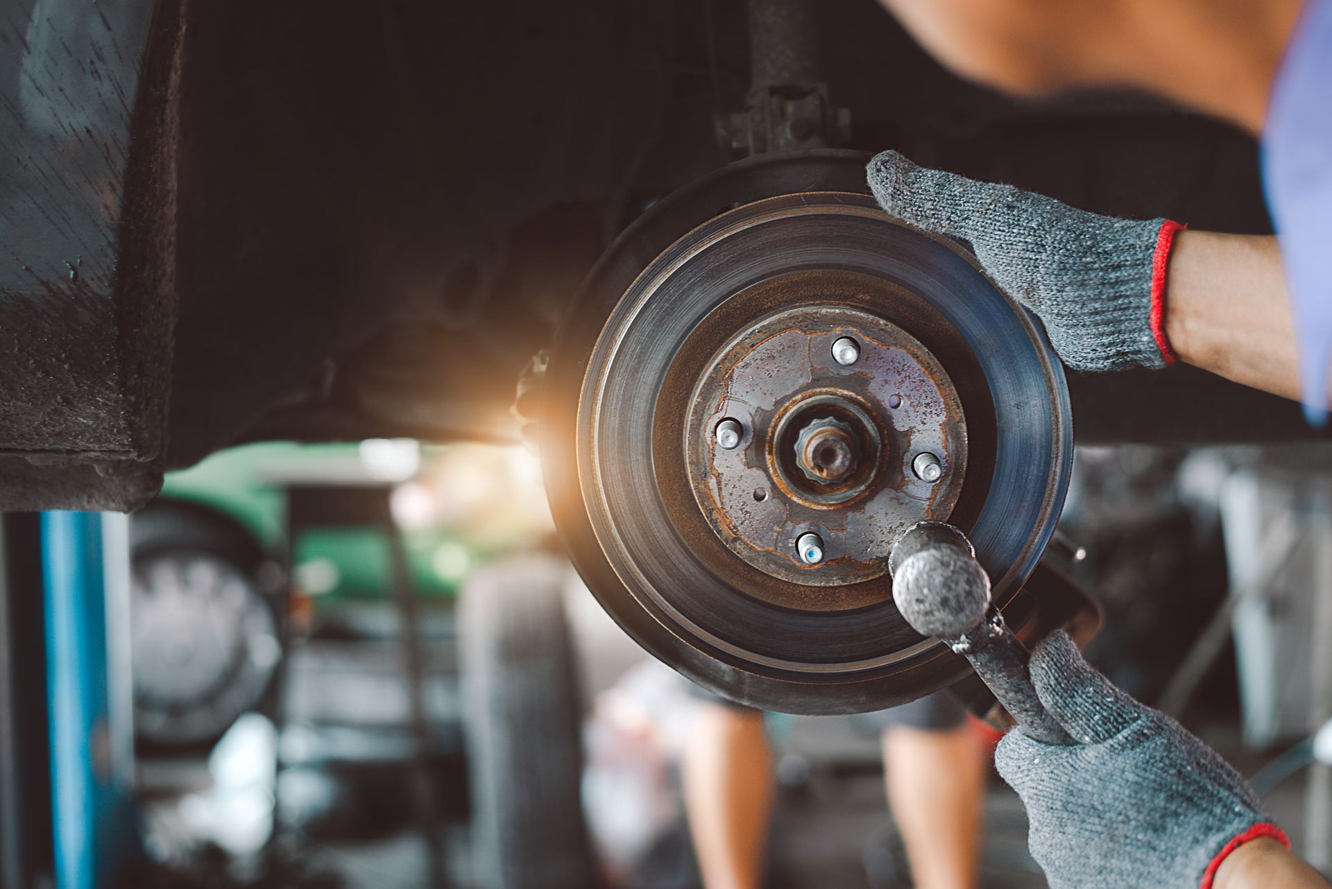 A man is fixing a brake disc on a car in a garage.