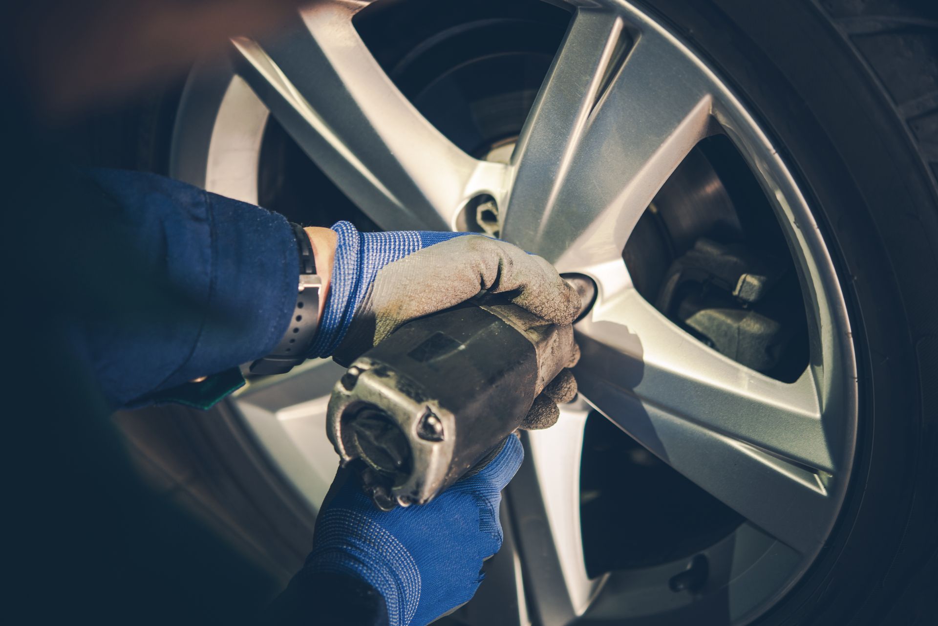 A person is changing a tire on a car with a wrench.
