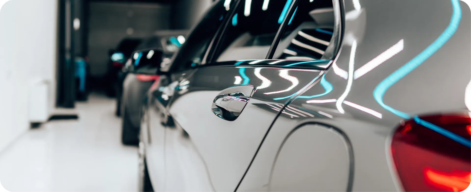 Gray McLaren sports car with gullwing doors open, parked on gravel.