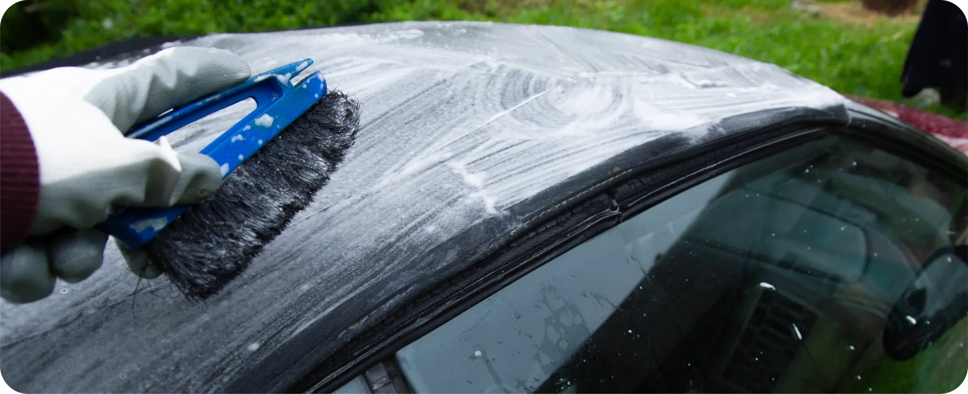 A red Bentley convertible parked on a gravel driveway with black rims and a black top.