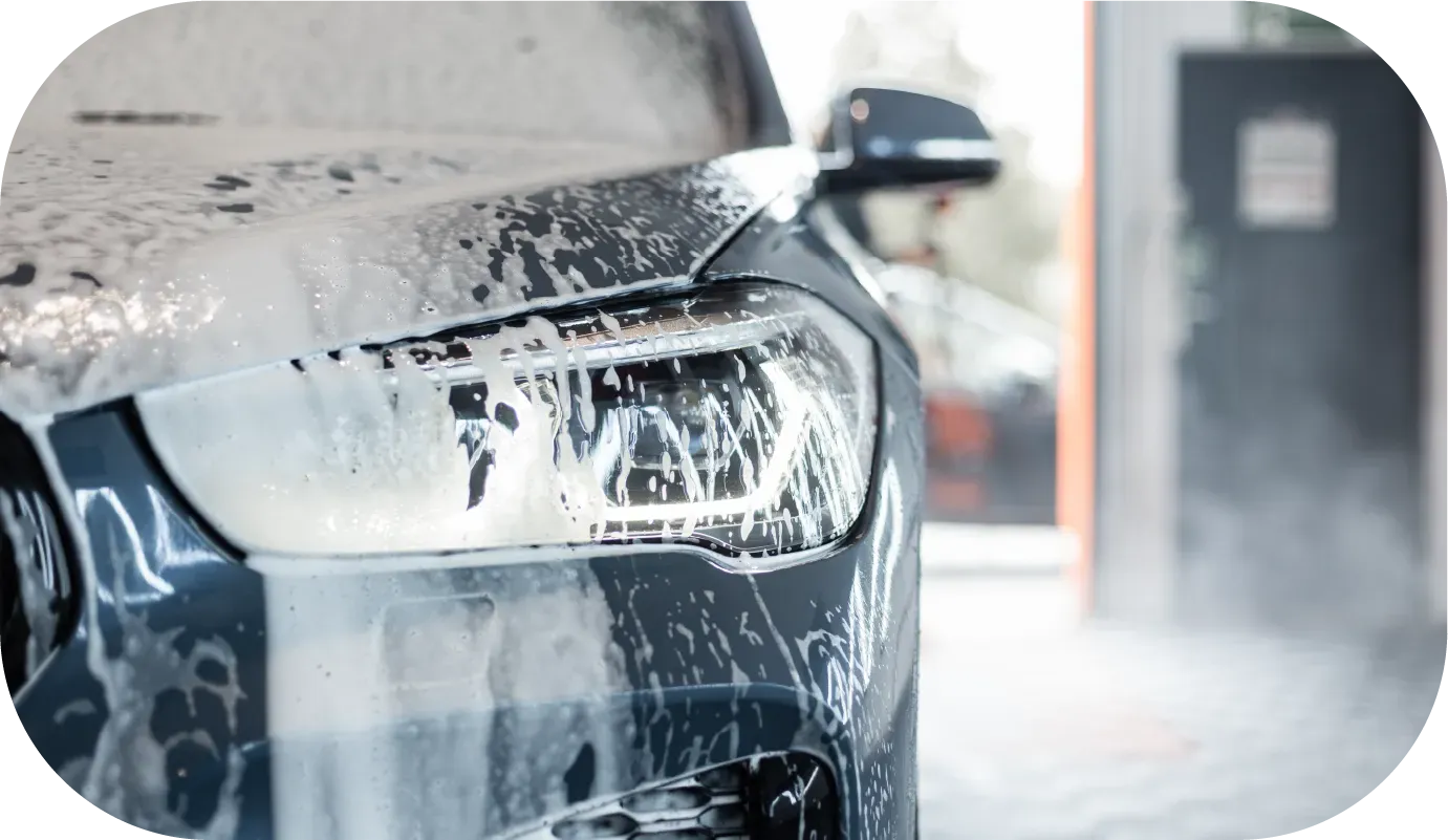 Black Audi RS4, silver wheels, parked near a green and white van, outdoors.