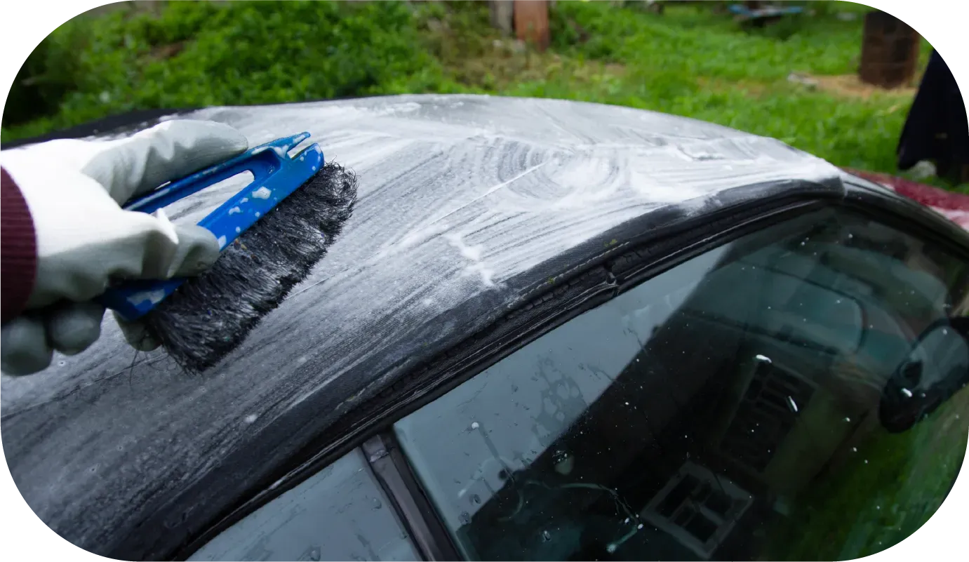 Red Bentley convertible parked on gravel.