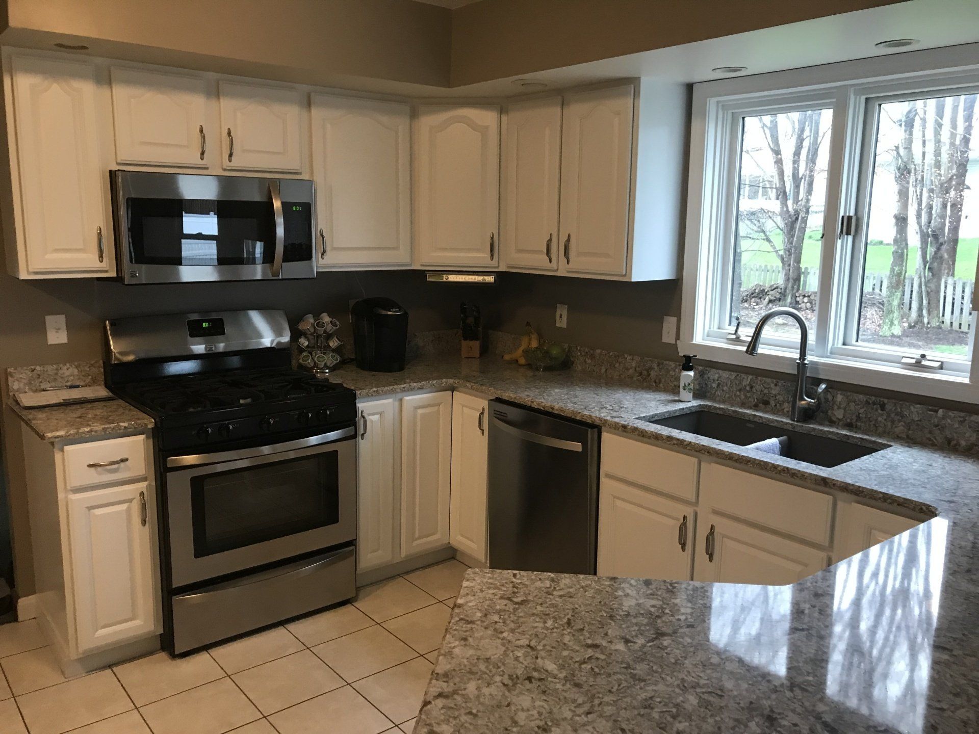 A kitchen with white cabinets , stainless steel appliances and granite counter tops.