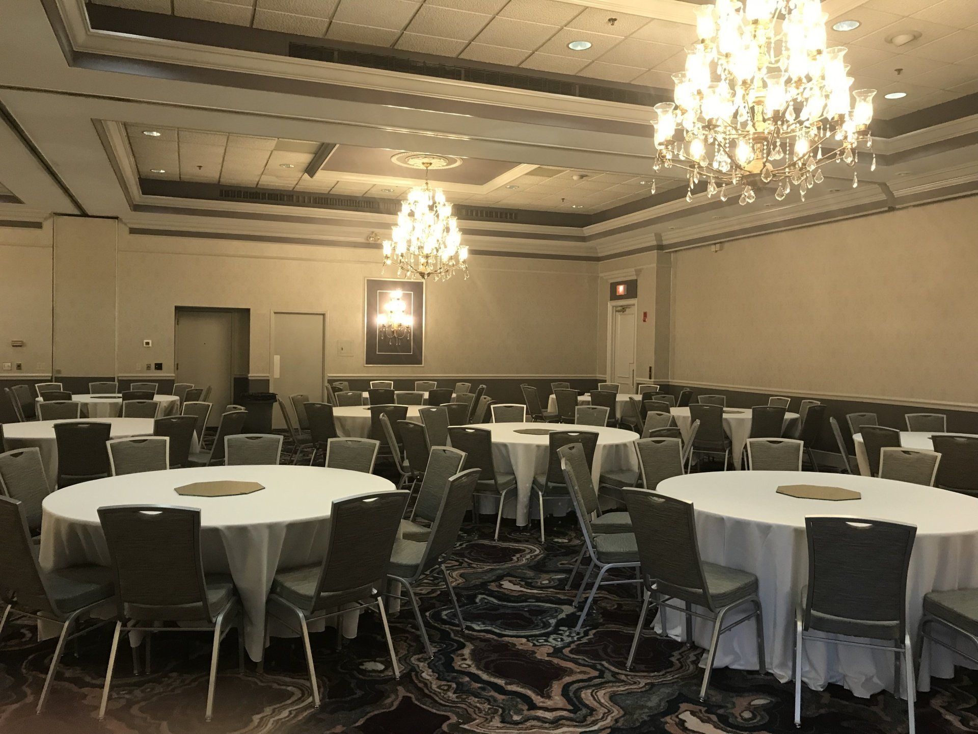 A large room with tables and chairs and a chandelier.