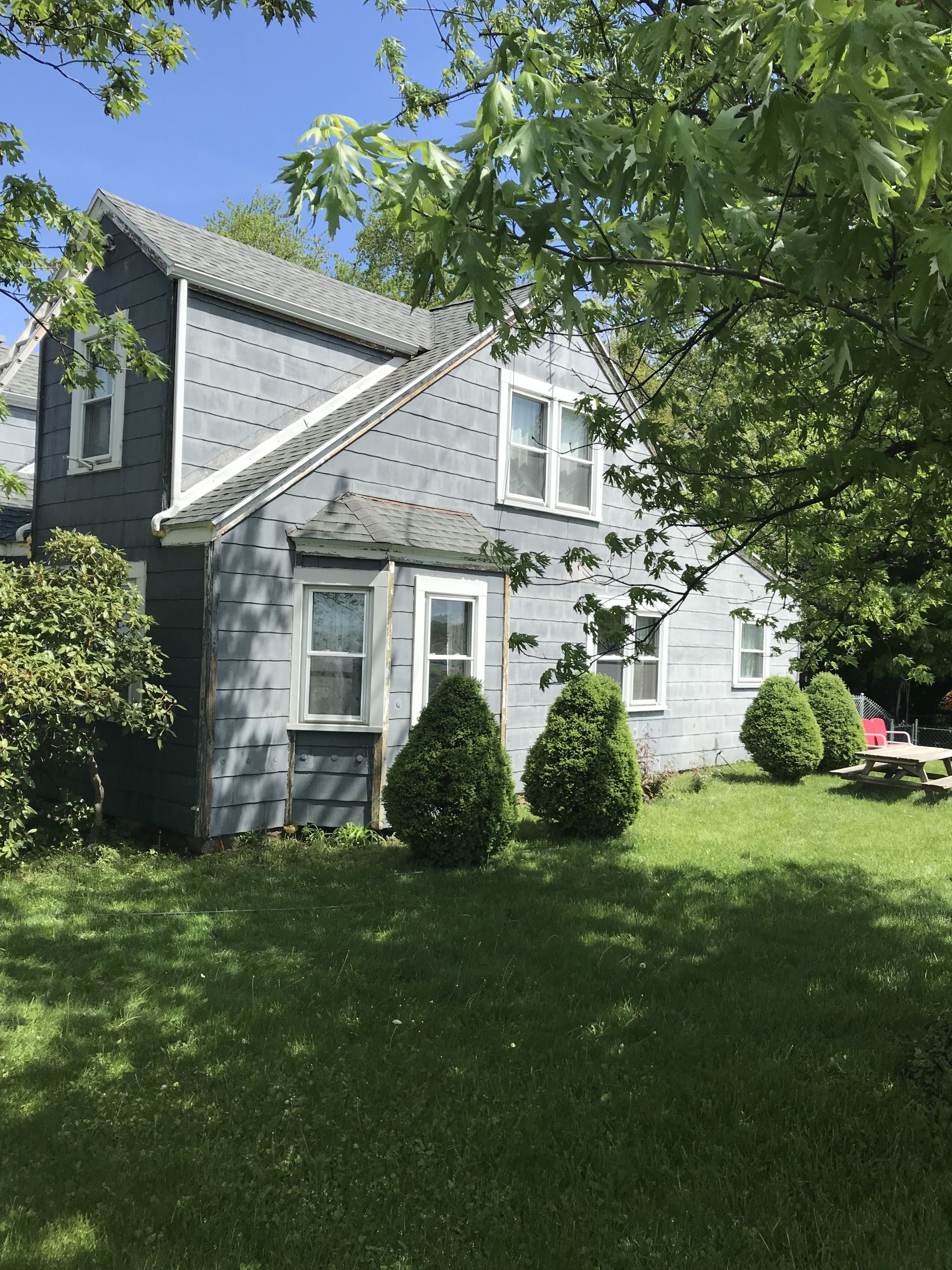 A gray house with a picnic table in front of it
